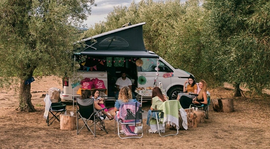 group of friends sitting around a camper van
