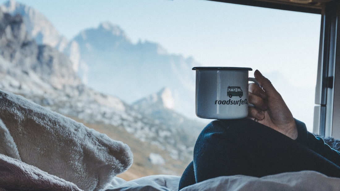 hand holding a cup of coffee in a camper van