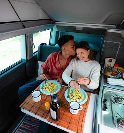 Happy Couple enjoying selfmade meal inside their campervan