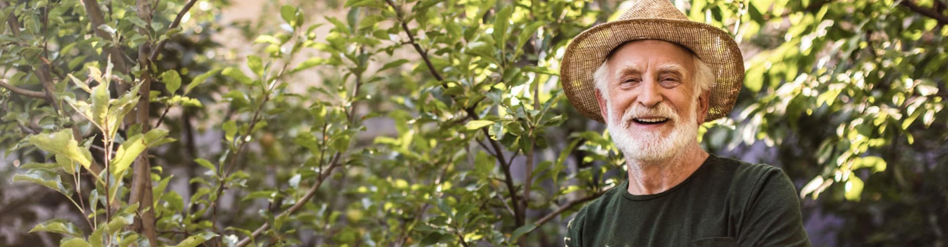 Happy host with hat standing in front of a green tree