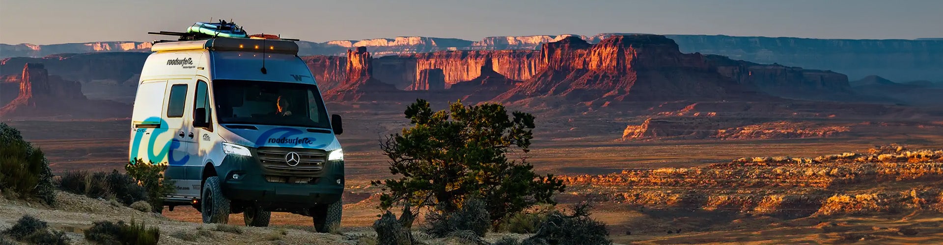 Horizon Hopper Off Road RV in the USA driving through a red stone and desert landscape at sunset