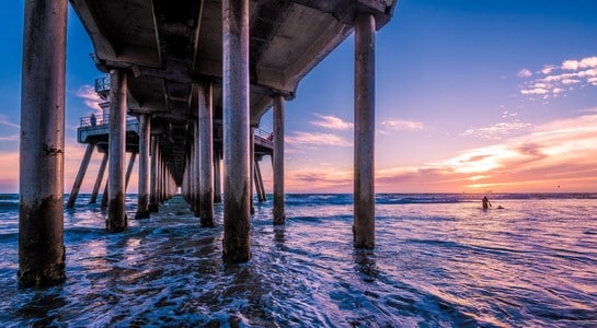 Huntington Beach Pier at sunset with surfers in the lineup, one of the best surfing spots in California