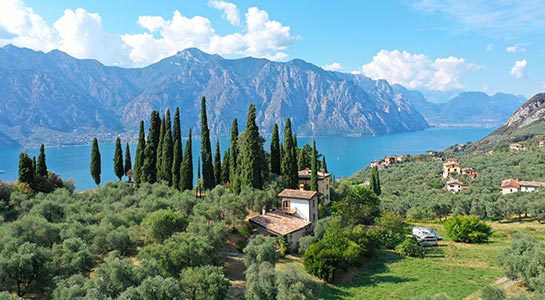 Italy, Lake Garda with mountains in the background and trees and houses in the foreground