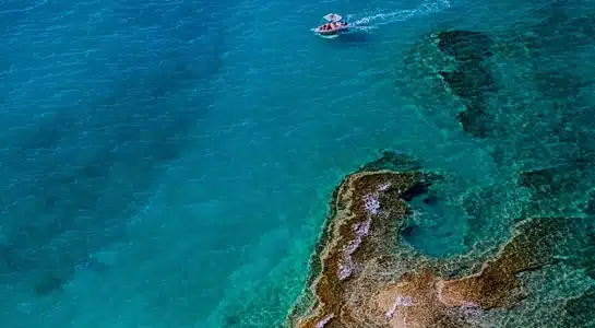 Small boat gliding across turquoise waters above coral reefs near Key Largo in the Florida Keys.