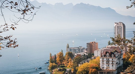 Landscape of buildings surrounded by the sea in Montreaux with mountains visible in the background.