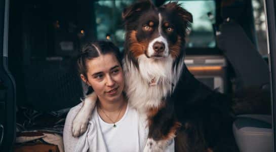 Woman sitting inside a pet friendly RV rental with a large dog resting beside her.