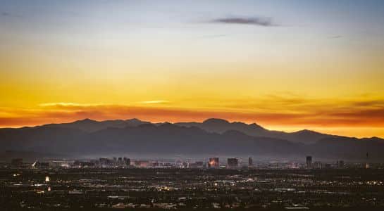 Las Vegas skyline at sunset with desert mountains in the background before beginning a Las Vegas to California road trip