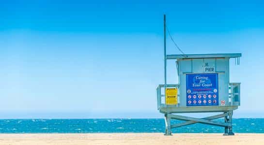 Iconic lifeguard tower standing against a bright blue sky at one of the sunniest beaches in LA.