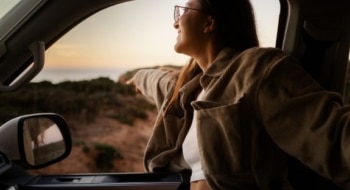 Woman enjoying a scenic drive during a long term RV rental road trip at sunset
