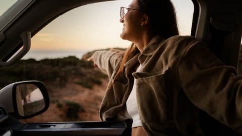 Woman enjoying a scenic drive during a long term RV rental road trip at sunset