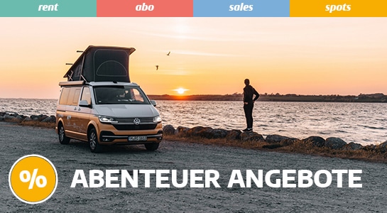 Man and VW campervan with Pop Up Roof by the water watching the sunset from
