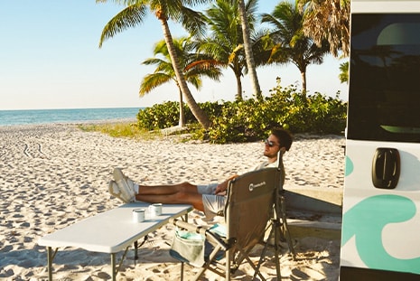 man-relaxing-on-beach-in-front-of-campervan