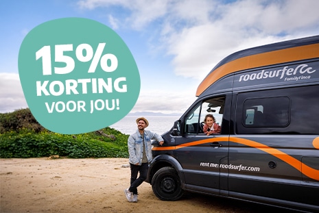 Man standing next to campervan parked at the beach with girl in car window