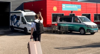 Man walking with luggage towards a roadsurfer station.