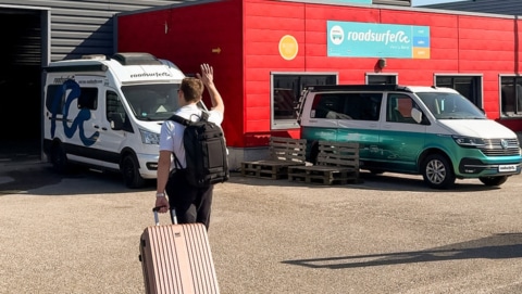 Man walking with luggage towards a roadsurfer station.