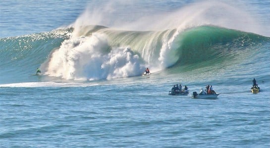 Surfers riding towering waves at Mavericks in Half Moon Bay, known worldwide for the best big-wave surfing in California