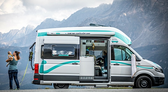 mother and baby next to a motorhome in a mountain landscape