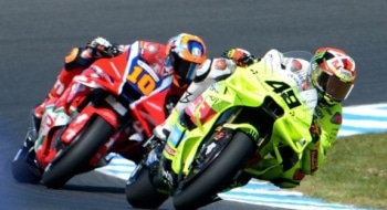 Two MotoGP riders leaning into a sharp corner during a close race on a professional circuit