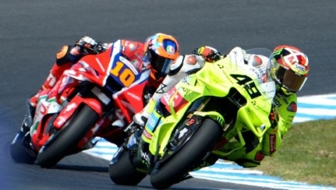 Two MotoGP riders leaning into a sharp corner during a close race on a professional circuit