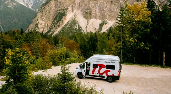 motorhome in front of a mountan and a forest