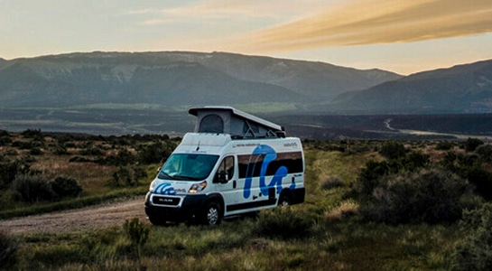Motorhome in USA between green grass and in front of small hills