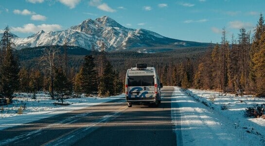 Roadurfer's motorhome driving on a lonely snowy road in the Rocky Mountains