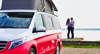 red van in the front, couple looking at the sea in the back
