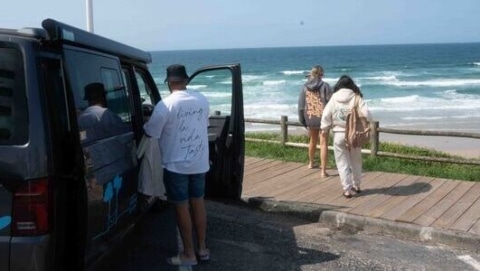 Some walking to the beach in front of a VW campervan looking into the sea of the northern coast in Spain