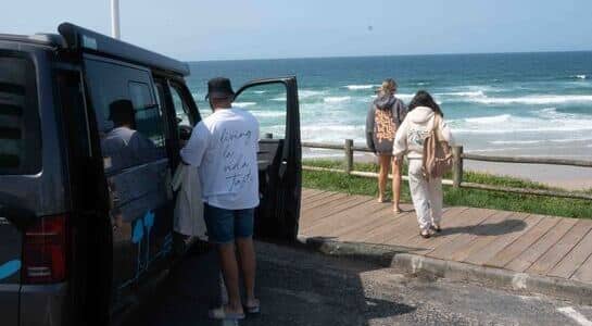 Some walking to the beach in front of a VW campervan looking into the sea of the northern coast in Spain