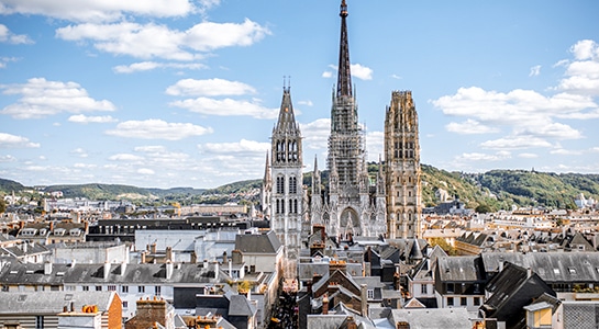 Overlooking the buildings in the french city Rouen with a church being located in the middle of the picture and hills in the background.