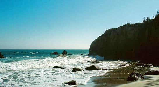 Waves crashing against rock formations at Paradise Cove, a hidden gem among beaches in LA.