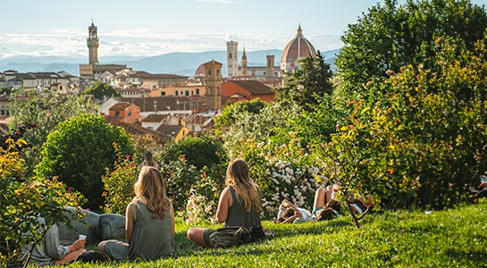 People sitting in a park with a view over the city of Florence.