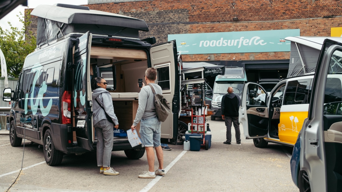 People checking the back of a campervan on a deal day before buying