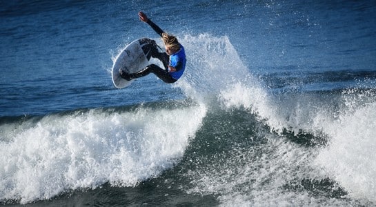 Surfer launching into the air above a wave at Pismo Beach