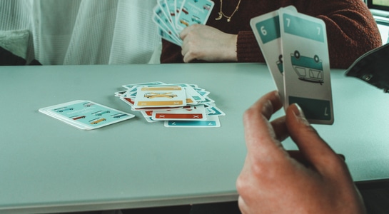 Two people playing cards around a table.