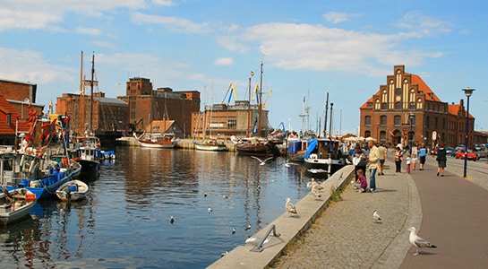 Promenade at the port of Wismar filled with people and seagulls.