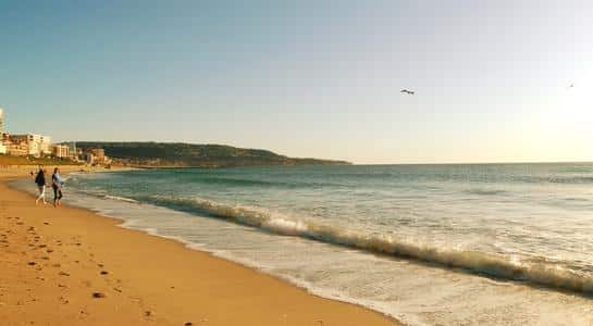 Waves rolling onto the sandy shoreline with people walking along Redondo Beach in Los Angeles