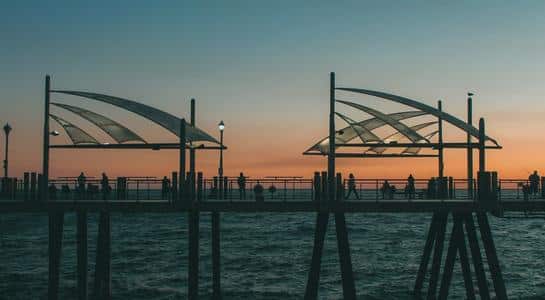 Silhouettes of people fishing and strolling at Redondo Beach Pier during a colorful sunset, a peaceful part of beaches in LA.