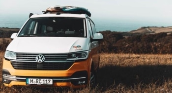 Orange camper van parked near the coast, showing what renting a camper looks like for flexible road travel