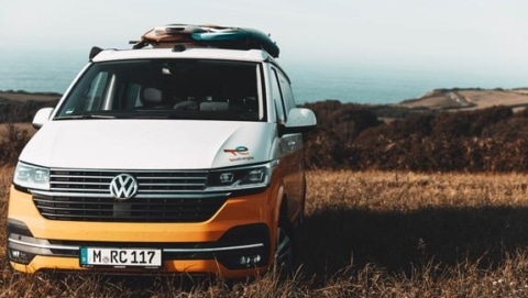 Orange camper van parked near the coast, showing what renting a camper looks like for flexible road travel