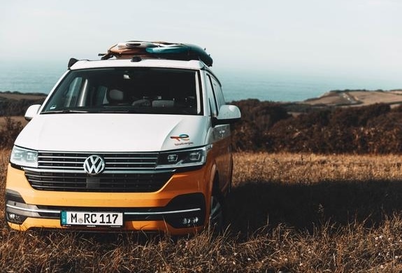 Orange camper van parked near the coast, showing what renting a camper looks like for flexible road travel