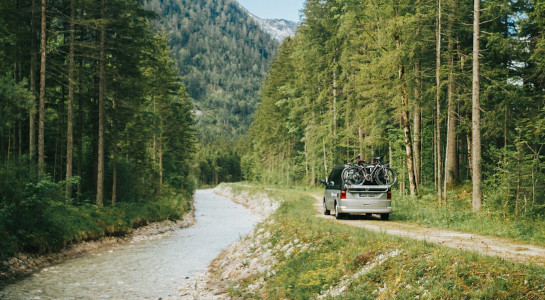 Camper driving next to a river and forest