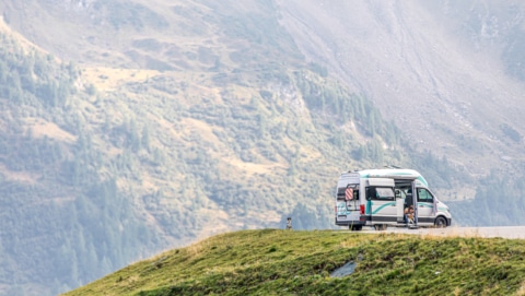 a white roadsurfer camper standing on a plateau in the mountains
