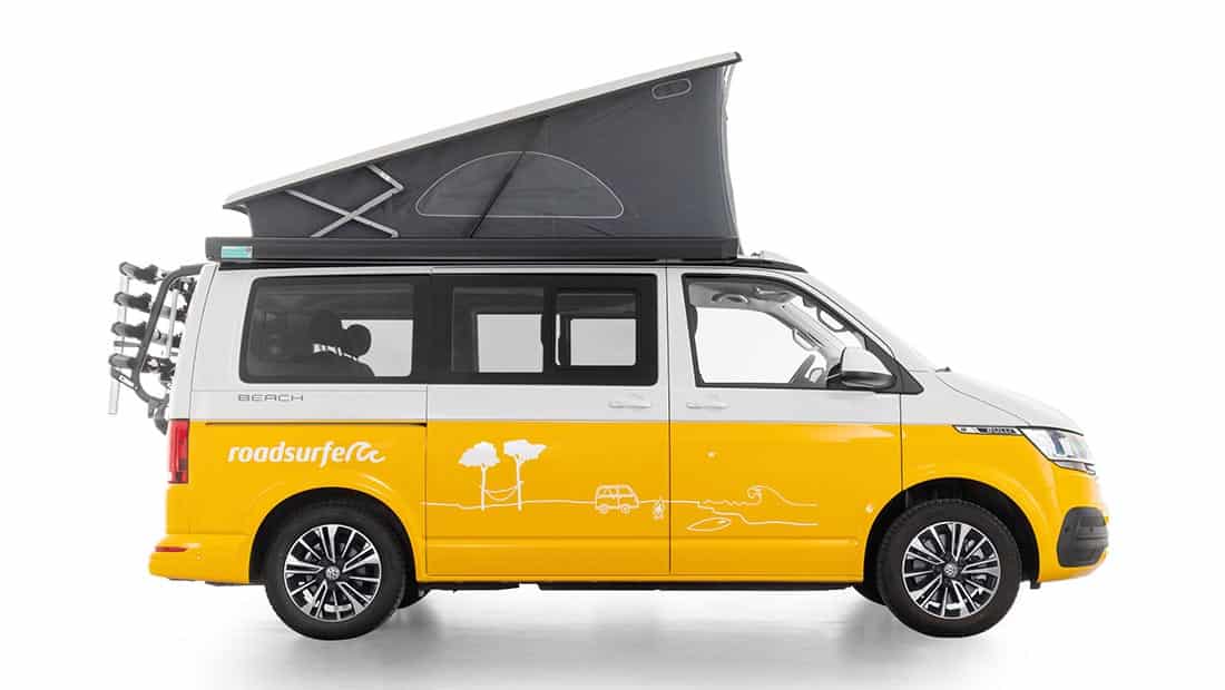 vw california beach as roadsurfer campervan beach hostel in yellow with pop up roof from the profile view