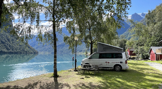 A white campervan parked by a lake in the mountains