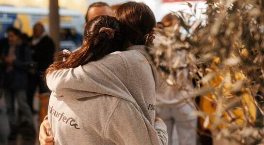 Two female roadsurfer collegues hugging.