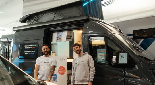 Two male roadsurfer collegues standing in front of boxvan.