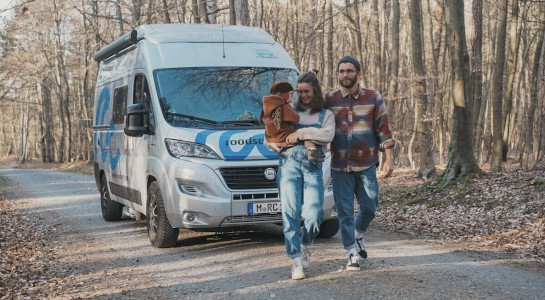 A family going for a walk in a forest, roadsurfer campervan in the background