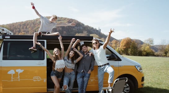young happy people in front of a yellow camper van