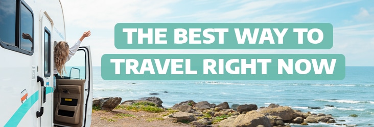 Woman looking out of a camper van towards the sea with the text "The best way to travel right now"
